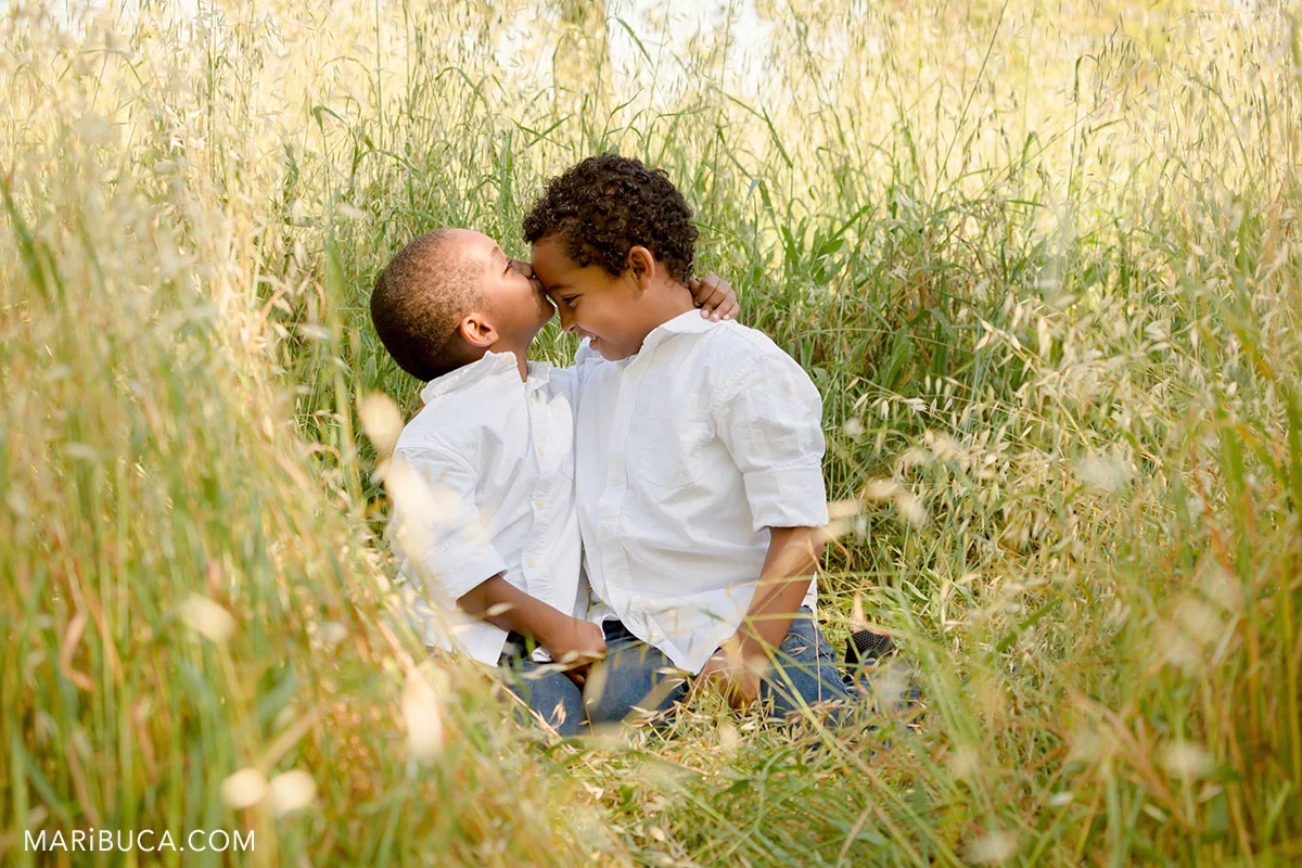 brothers show how their care about each other in the park. One of them kissing his brother in the forehead.