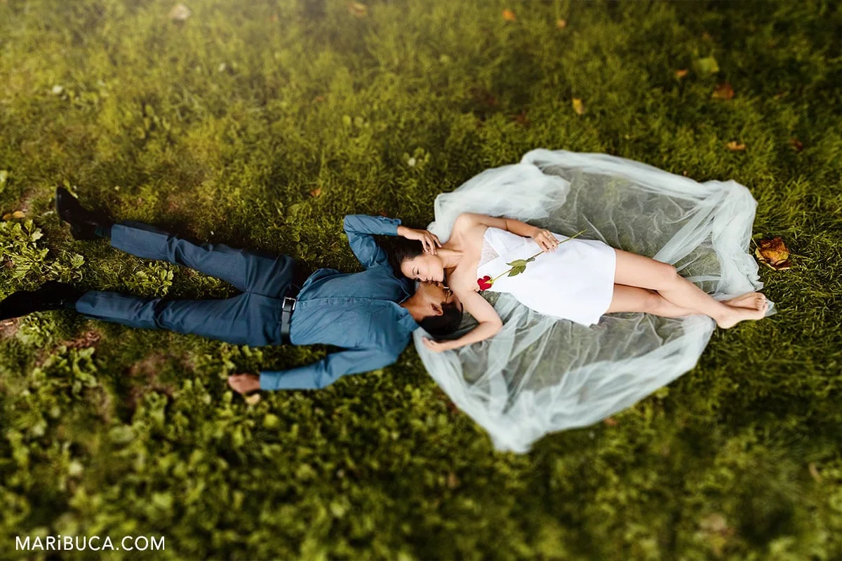 couple lay down in the grapp and kissing. Wedding kiss in the grass.