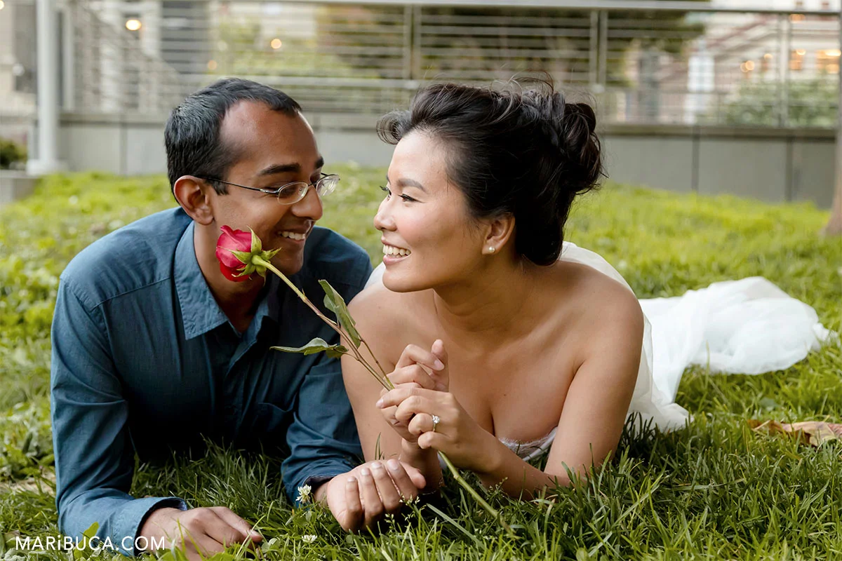 the fiancee and fiance lay down in the grass near Macy's down town in the Sand Francisco
