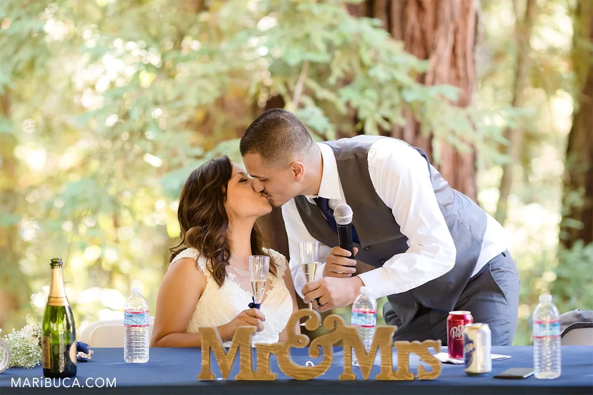 outdoor wedding bride and groom kiss each other. THe wooden signs in the table as Mr & Mrs