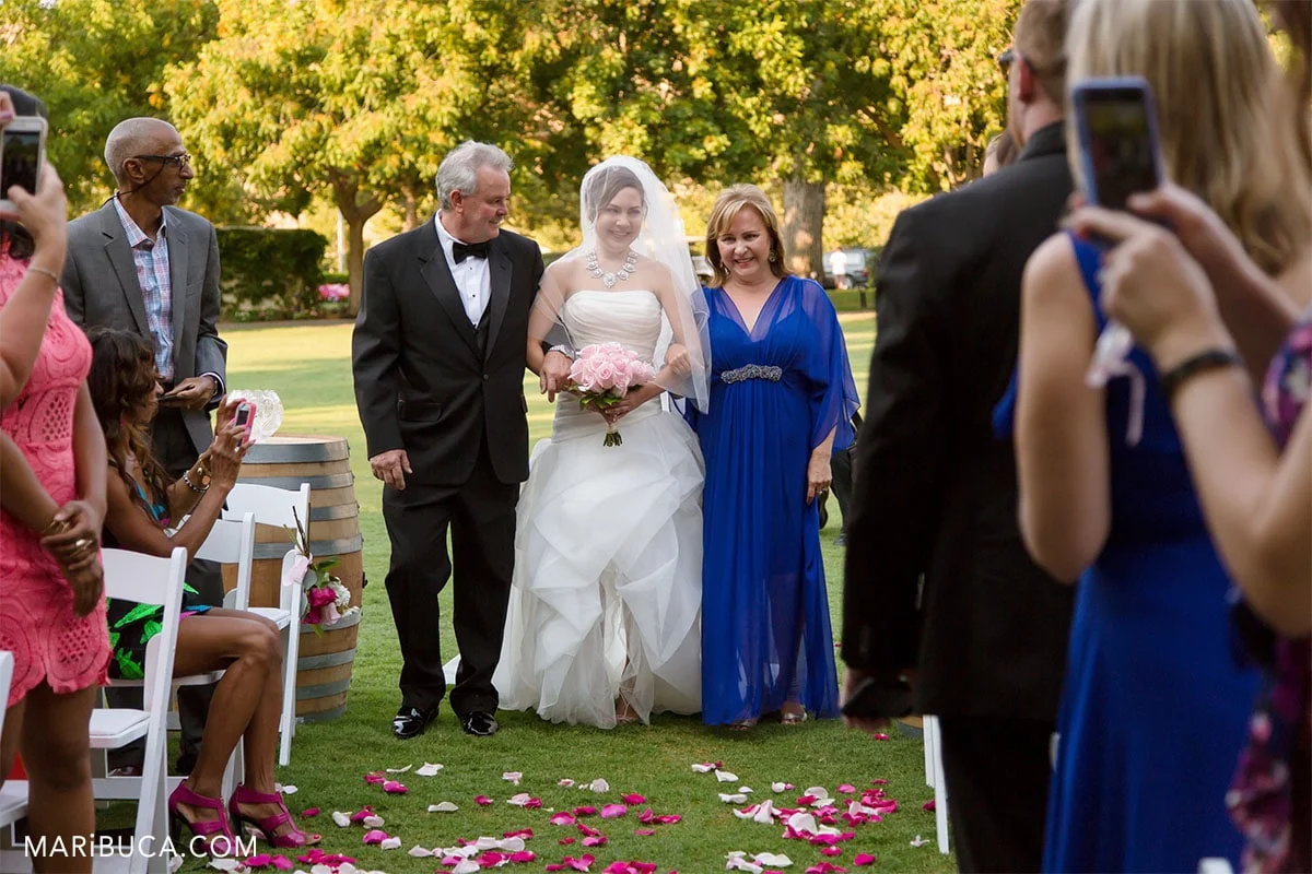 The gorgeous bride going down the aisle with her parents in the Wente Vineyards, Livermore, California