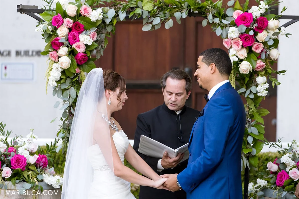 Amazing bride and handsome groom look each other in the ceremony. In this moment officiant read documents.