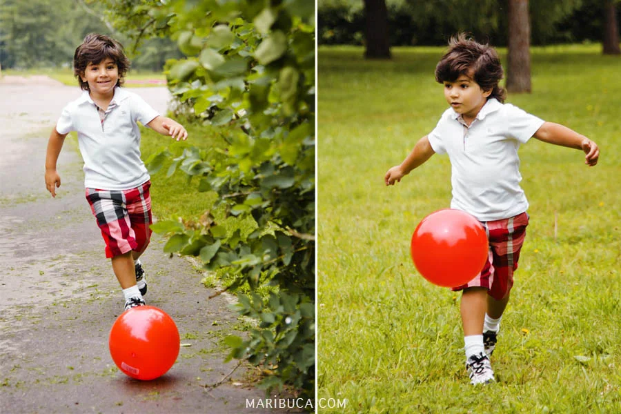 Boy in white shirt and shorts in a cage plays a red ball on green grass.