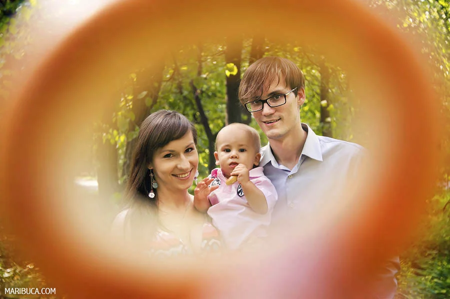 Family of the three together with orange rounded frame in the garden
