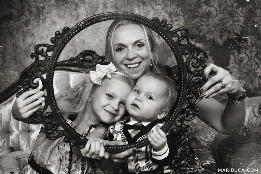 Retro photo where mom and her children laugh and look through the round frame.