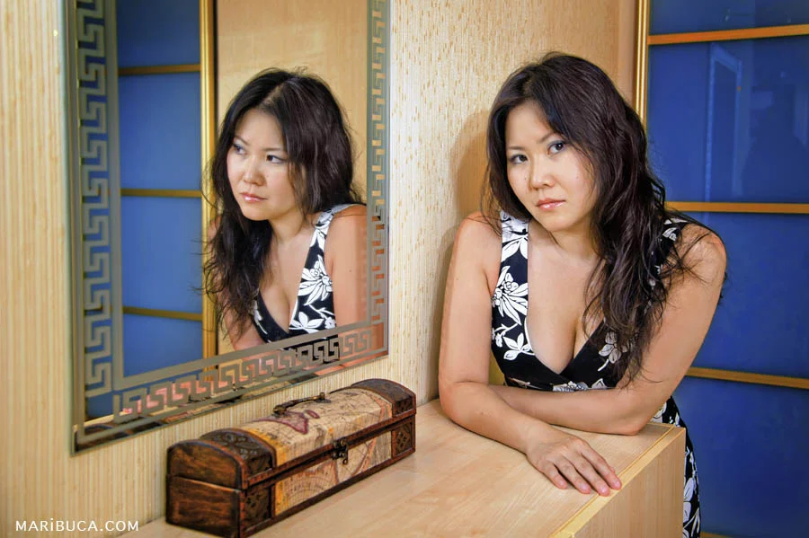 Portrait of a girl with long with her reflection in a mirror in beige and blue tones