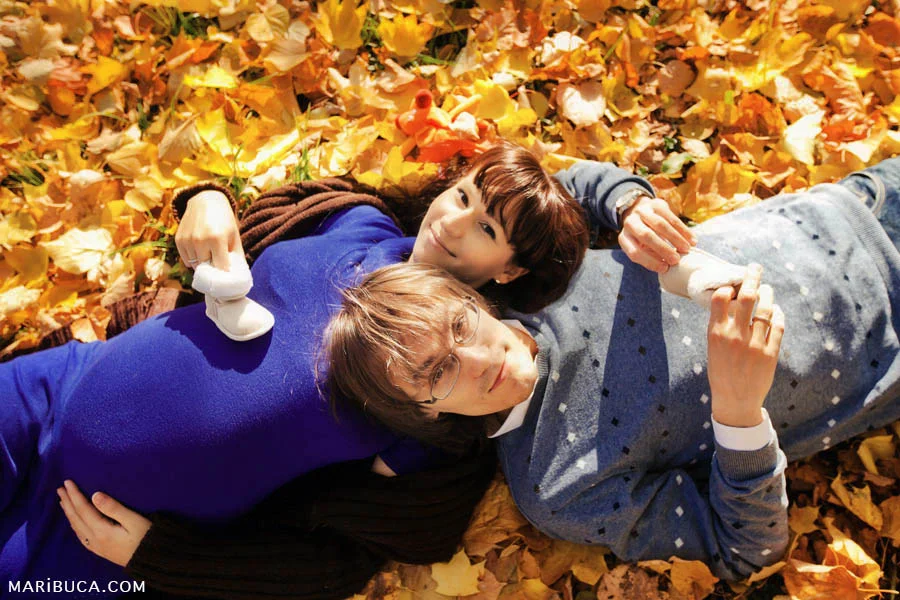 Pregnant girl and her husband lie on the yellow-orange leaves in San Francisco