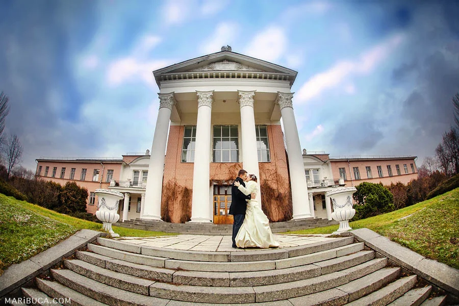 bride and groom on nature in the park kiss each other against the background of the historic building in Hayward