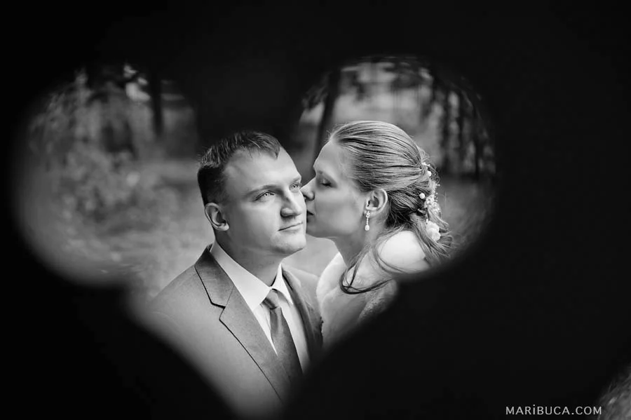 The bride kisses the groom and the heart around them as a symbol of love and eternity.