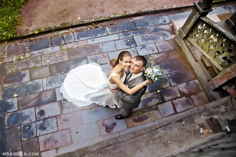 newlyweds stand and look up among the colorful, textured tiles around them.