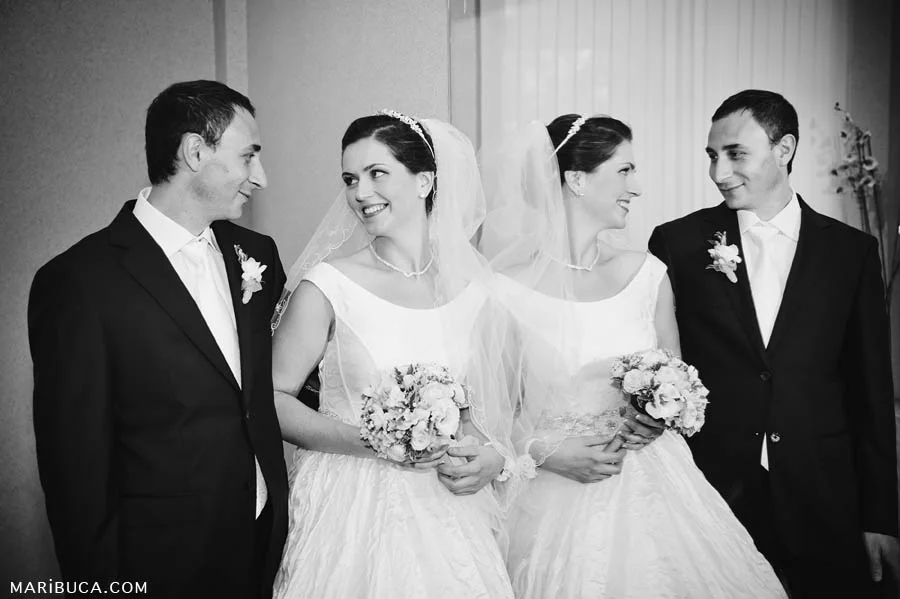 Black and white photograph of the bride and groom are standing next to each other and their reflection in the mirror.