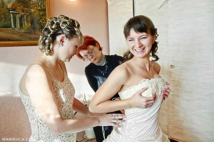 Bridesmaids help the bride during the getting ready