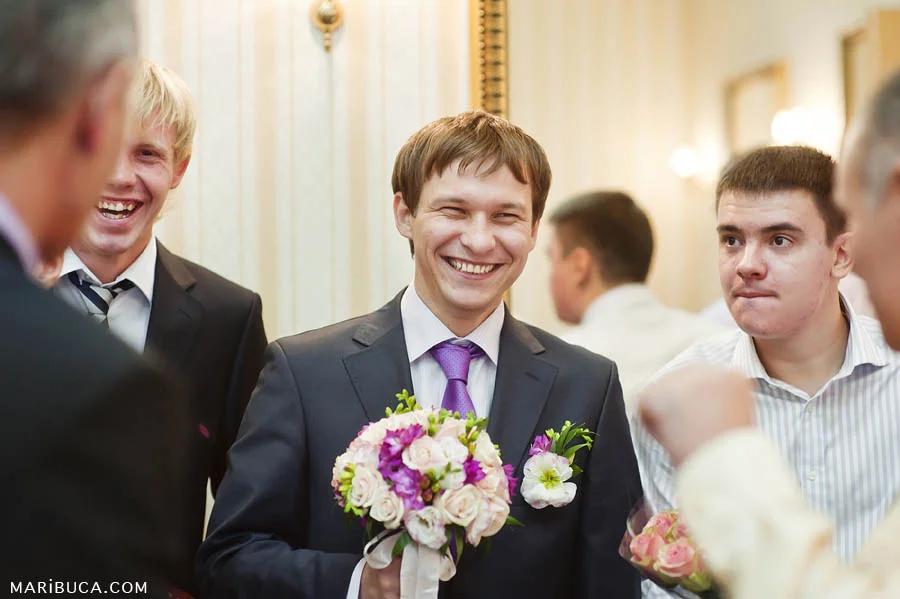 The groom laughs with friends in the registry office