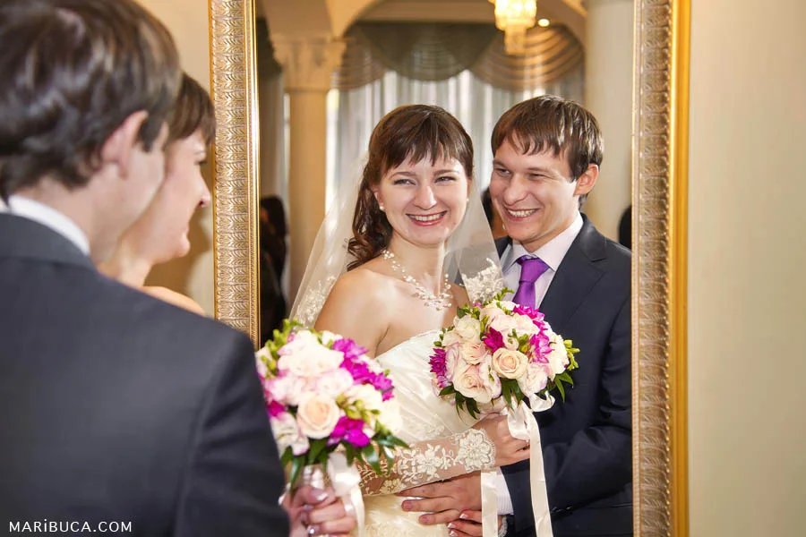 The bride and groom together look at themselves in the mirror in the registry office.