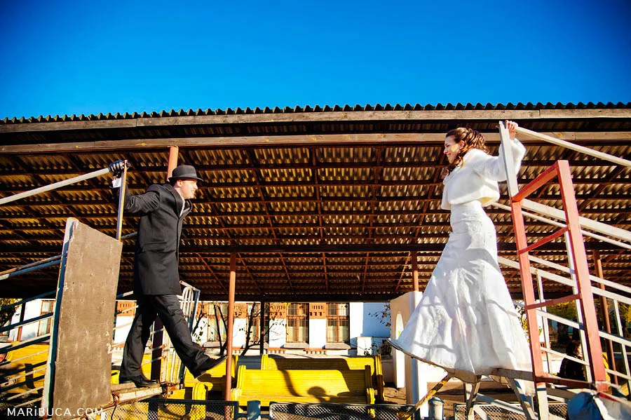 The bride and groom are drawn to each other in an industrial area.