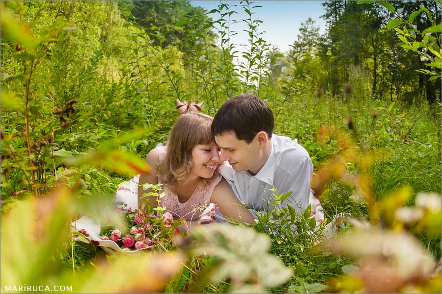 The fiancee and fiance lay down in the grass and enjoy each other company in the Shoreline Park.