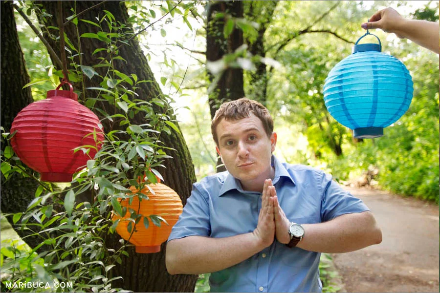 a guy fooling around on the background of Japanese lanterns in the trees in the forest