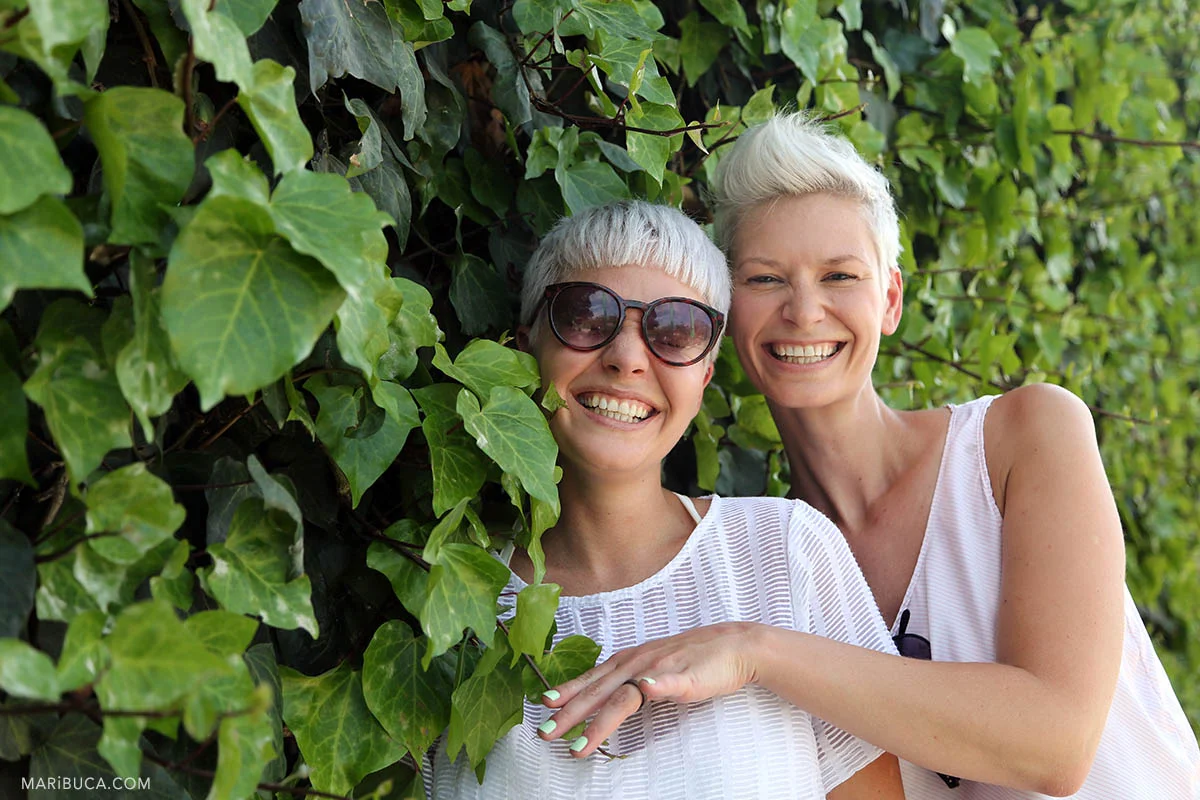 Girls have fun when a couple of newlyweds are surrounded by green bushes.