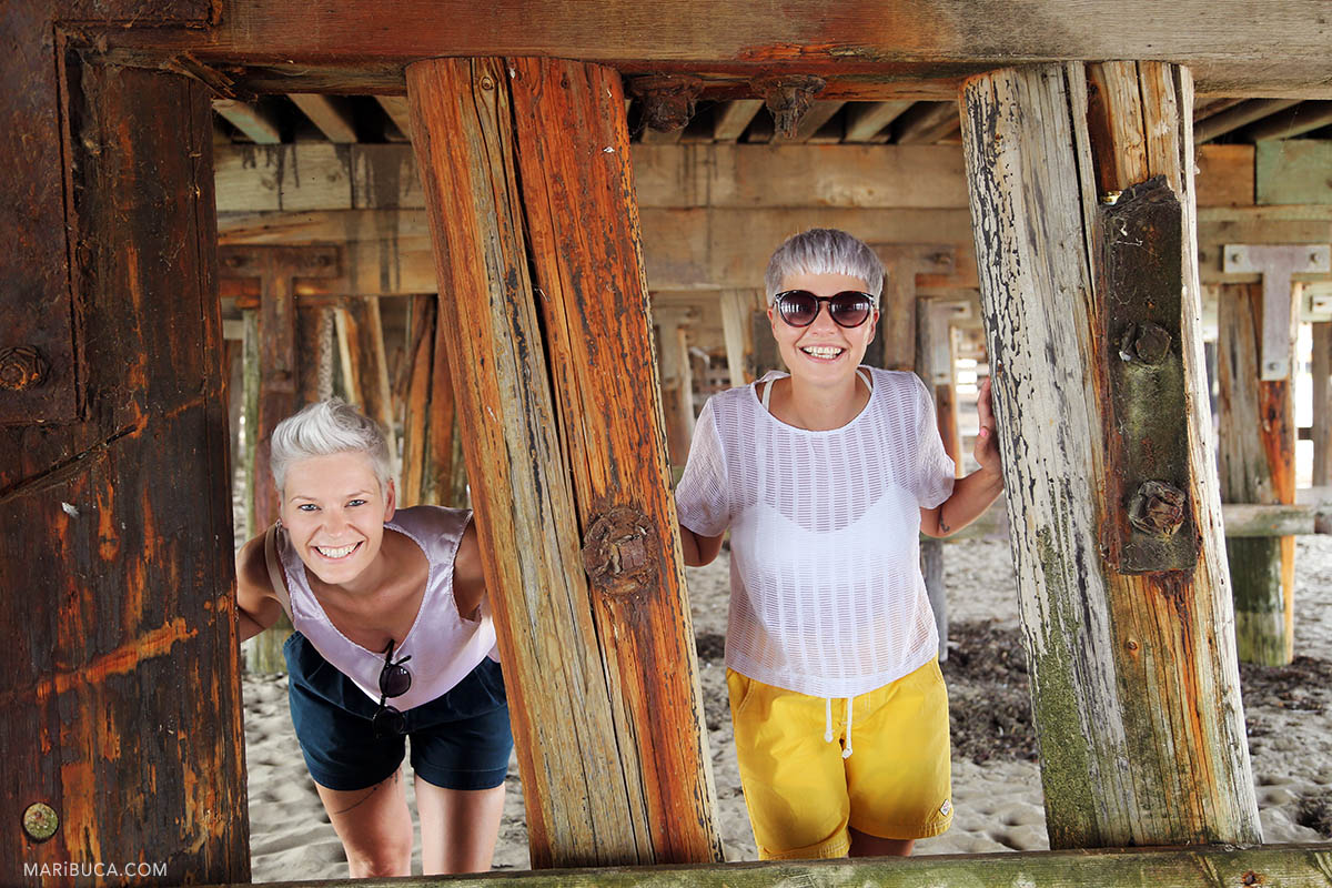 Happy brides after wedding ceremony posing for pictures under the old bridge.