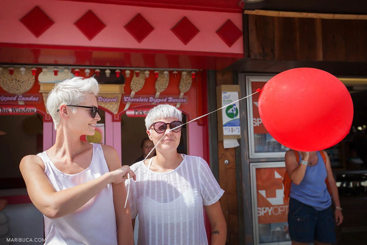 Girls have fun with red balloon during their wedding walk in the Boardwalk's Cocoanut Grove, Santa Cruz .