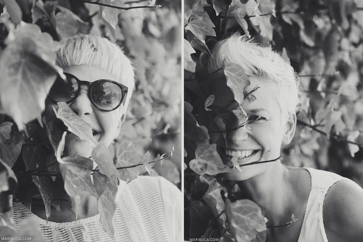 Black-and-white photography of a portrait of girls laughing and having fun in the bushes with leaves.