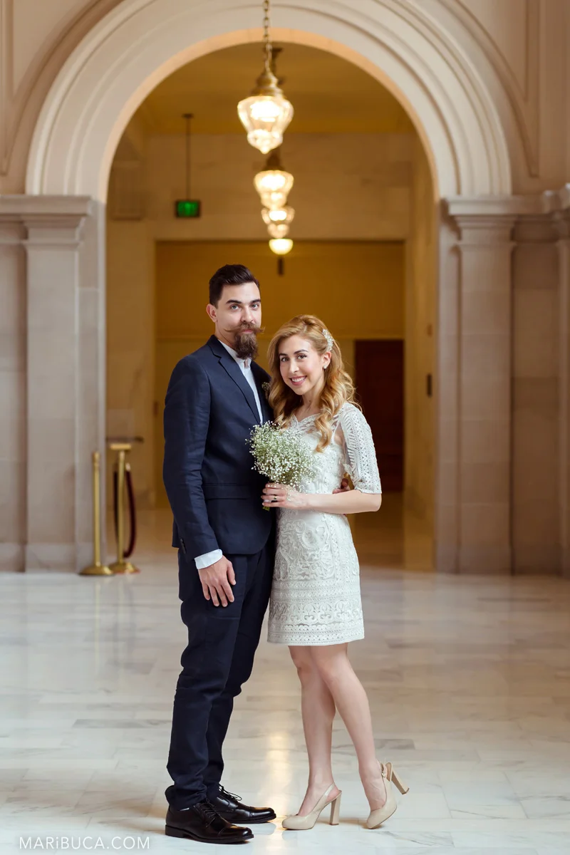 Romantic couple: the bride and groom stand in an embrace against the background of the arch in the SF City Hall in San Francisco