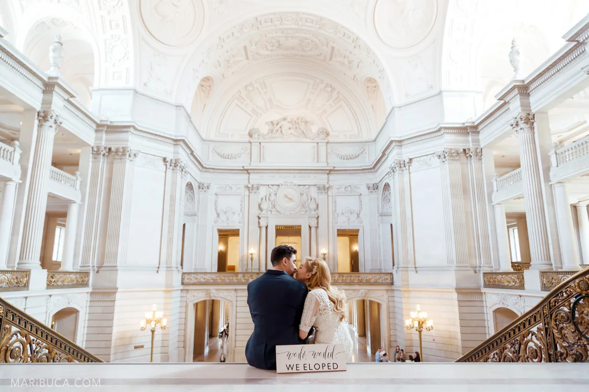 Sign we do, we did, we eloped! The bride and the groom are sitting in the stairs and kissing each other
