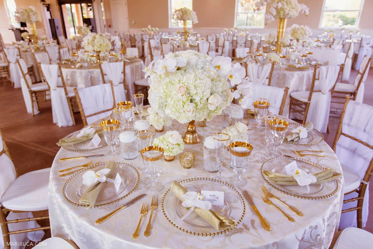 Reception details with white tablecloth and flowers, golden silvers and white flowers