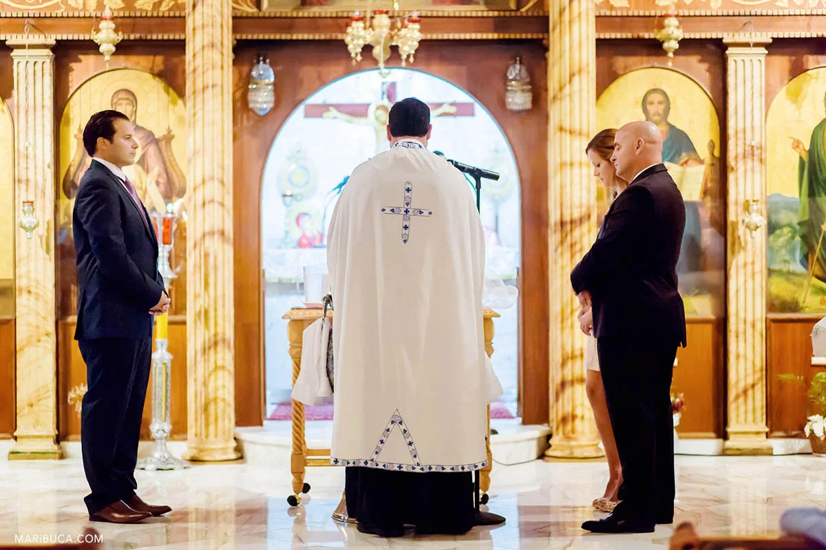 Guests and priest praying in the church before baptism.