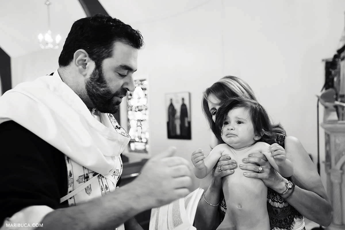 The girl is crying during Greek Orthodox baptism in the St Nicholas church