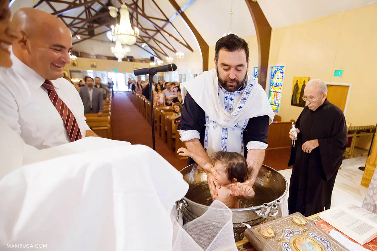 Baby girl is crying during dipping child in the water in the Greek Orthodox church.