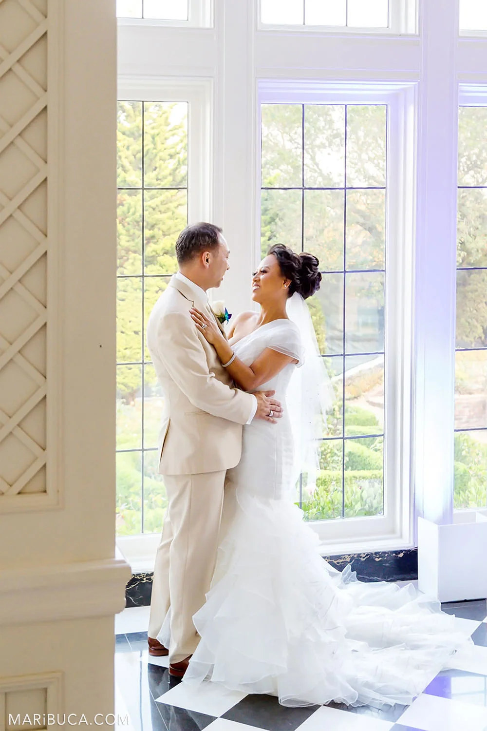 Groom and bride smile and stay in front of big windows with an amazing view inside in the Morning Room, Kohl Mansion, Burlingame