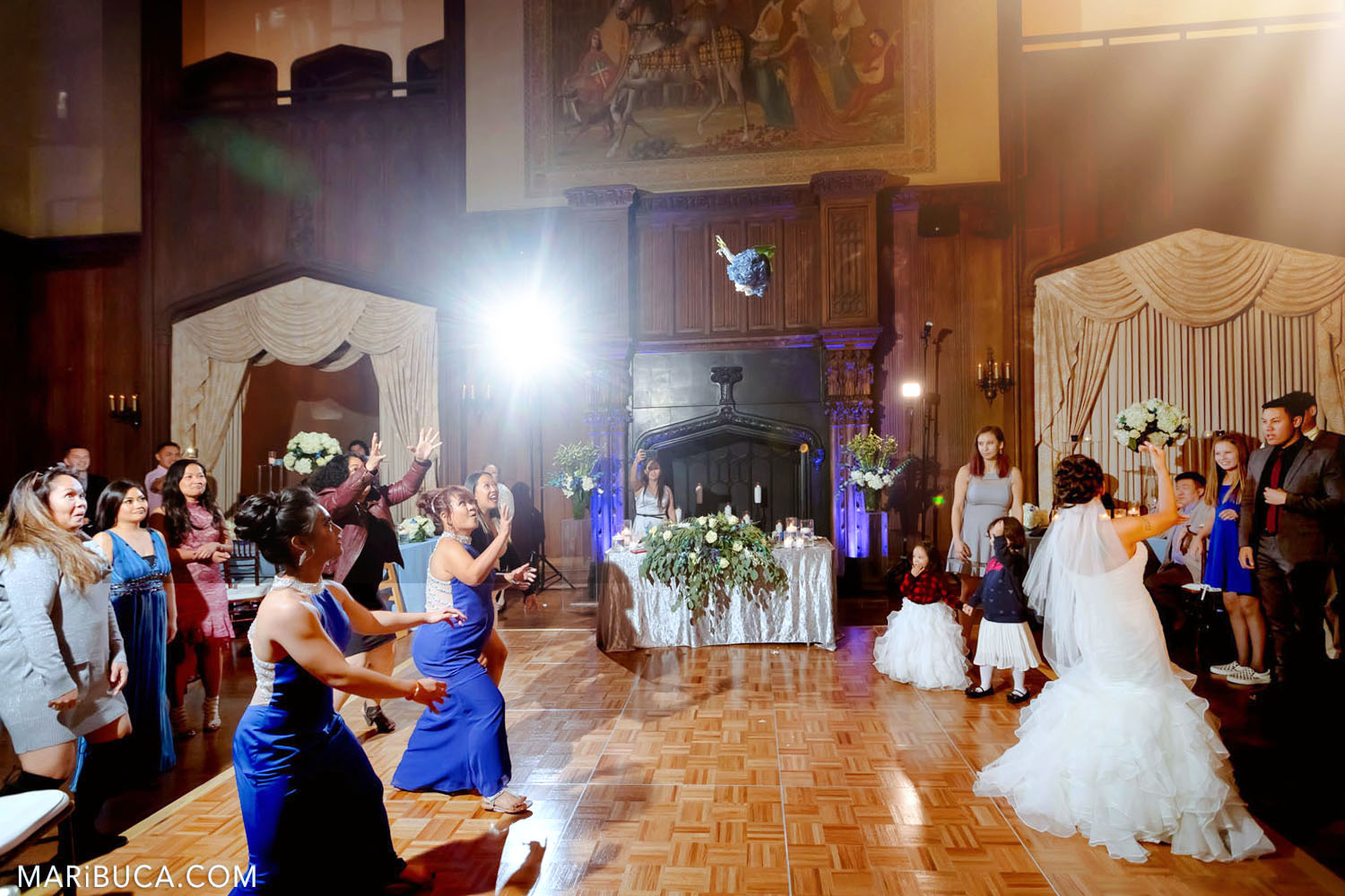 The bride tosses wedding bouquet to friends and bridesmaids in the Great Hall, Kohl Mansion, Burlingame