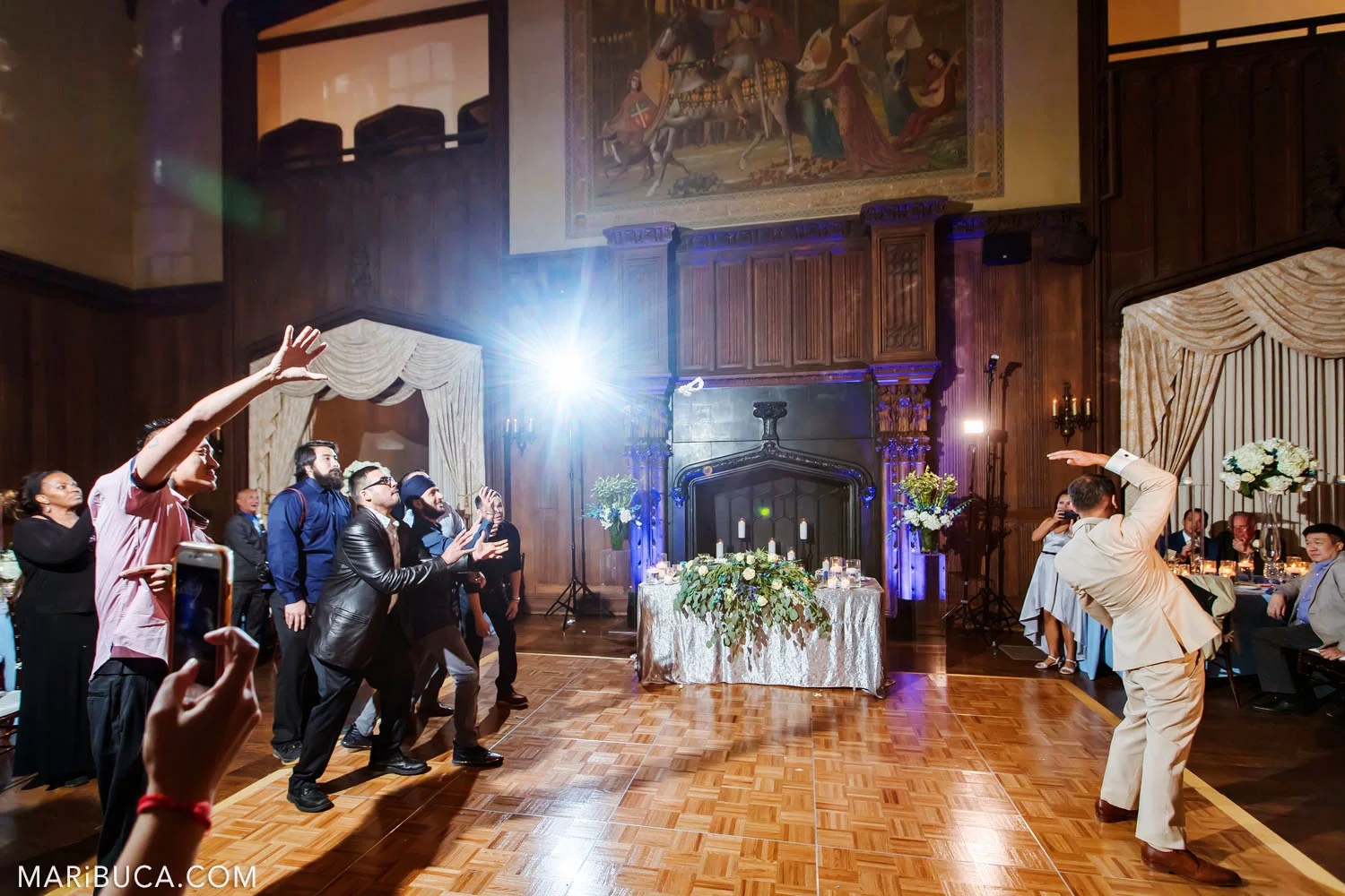 The groom tosses wedding bouquet to friends in the Great Hall, Kohl Mansion, Burlingame