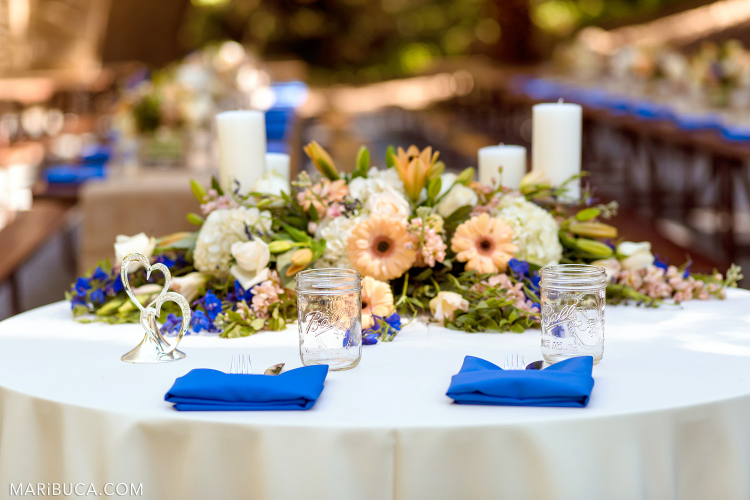 Wedding decoration of tables with white tablecloths, navy blue napkins, white candles in the Saratoga Springs Wedding