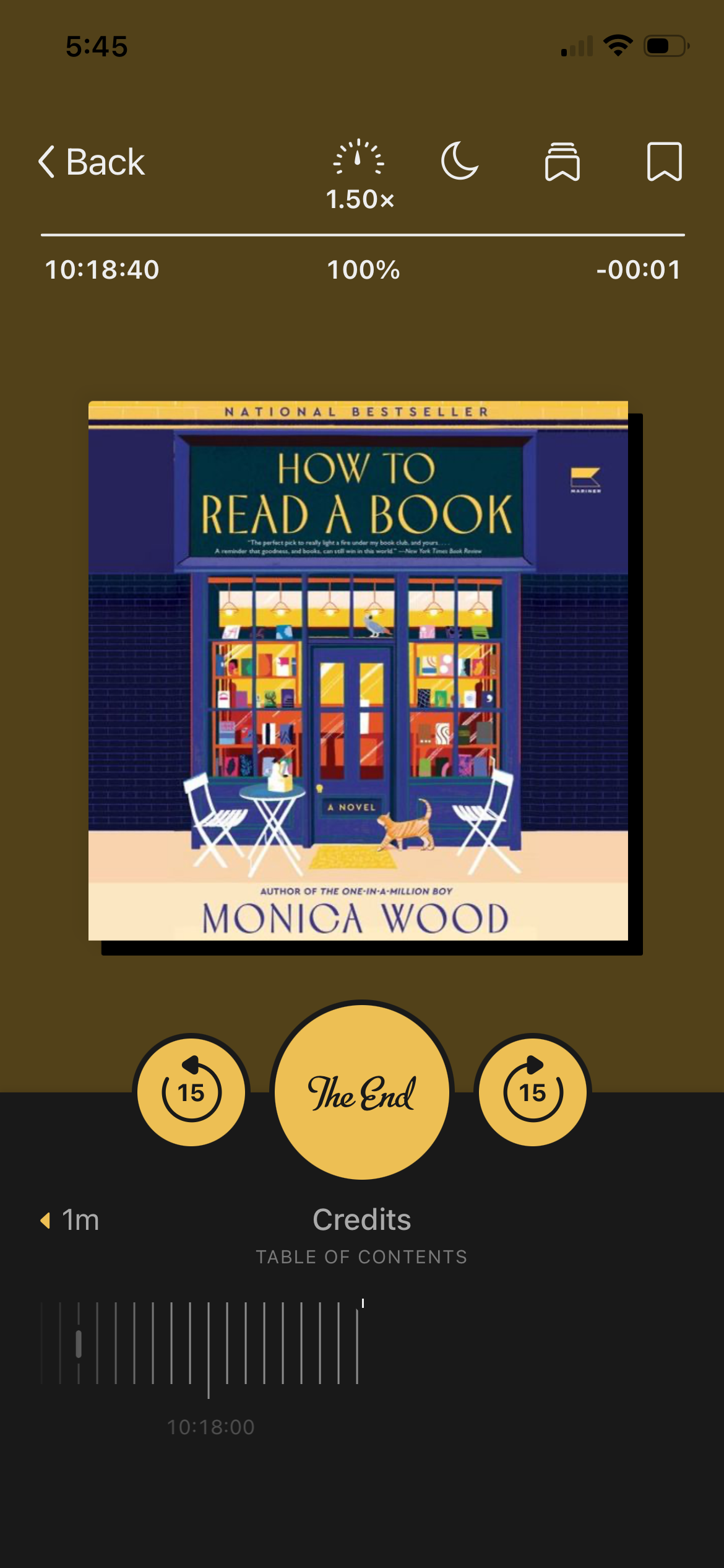 A screenshot of the audiobook How To Read a Book by Monica Wood in the Libby app. The cover shows a blue bookstore with an orange cat out front.