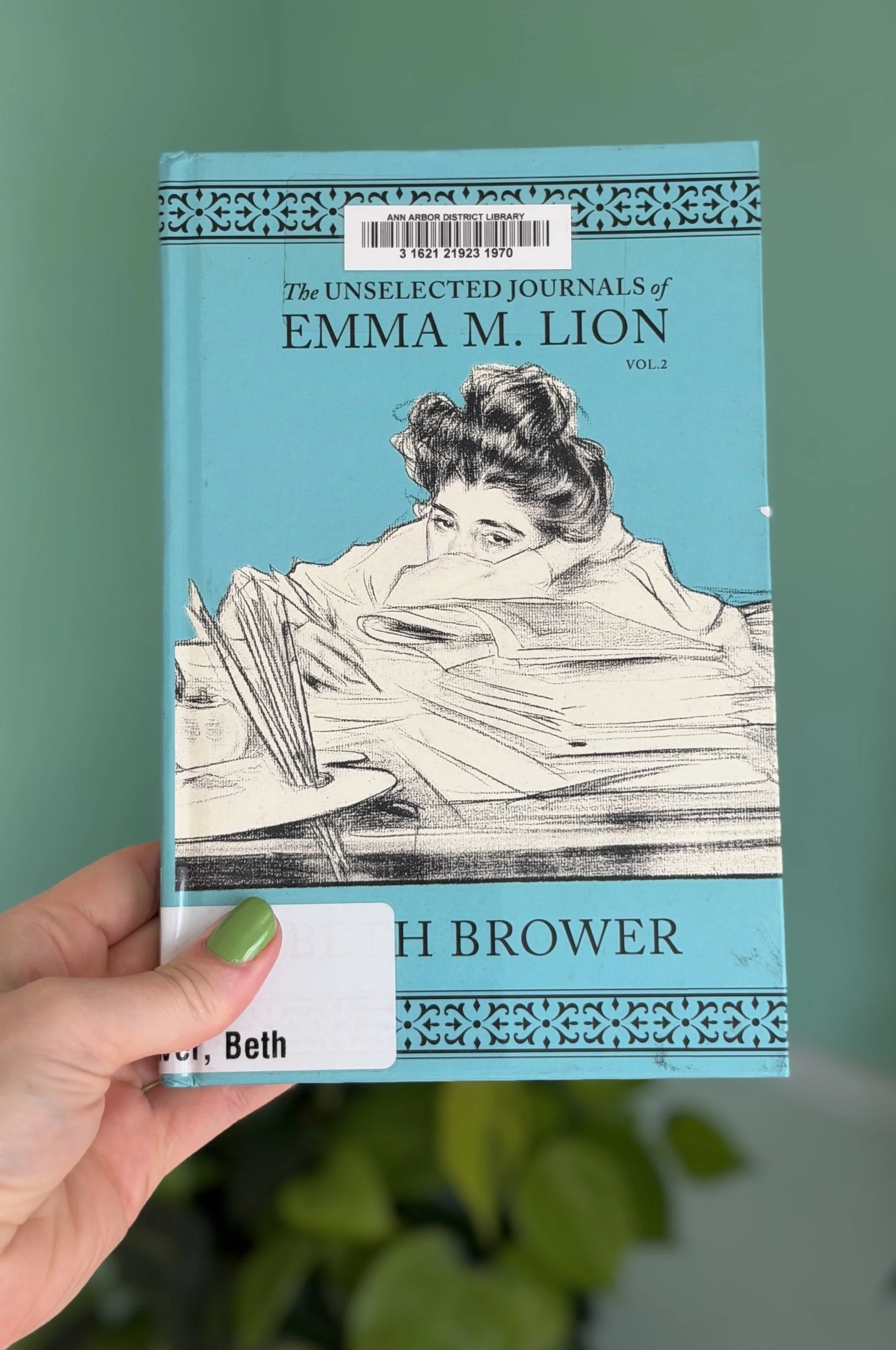 My hand holds a copy of The Unselected Journals of Emma M. Lion Vol. 2 by Beth Brower.