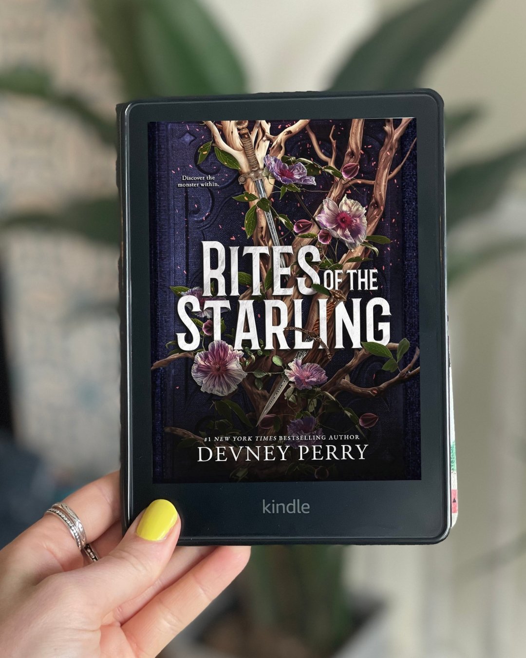 My hand holds a Kindle with Rites of the Starling by Devney Perry on its screen.