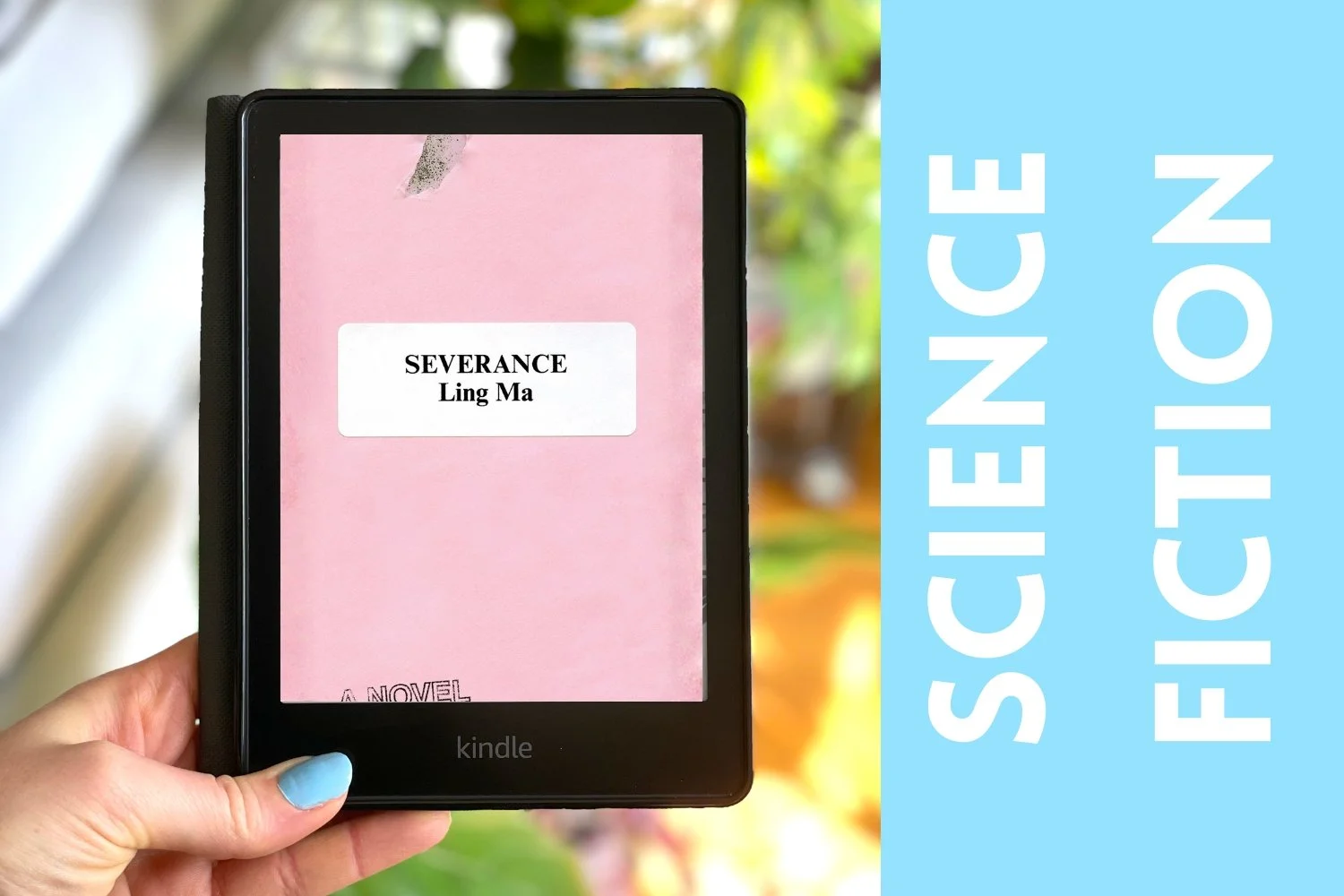 My hand holds a Kindle with a pink book cover on its screen. There is a blue bar on the side that says Science Fiction.