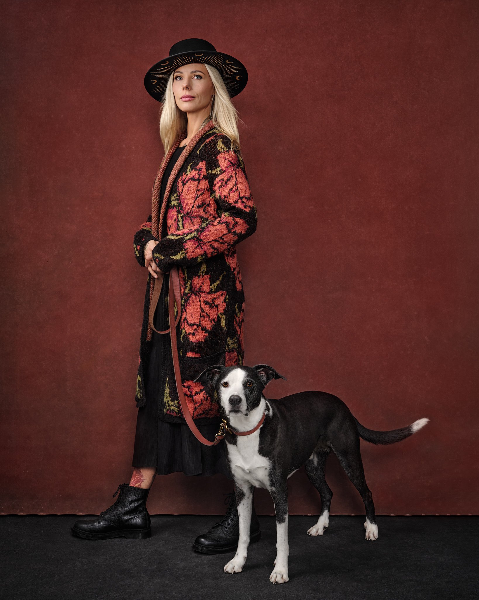 blonde-woman-with-black-and-white-dog-portrait-red-background-standing-with-leash.jpg