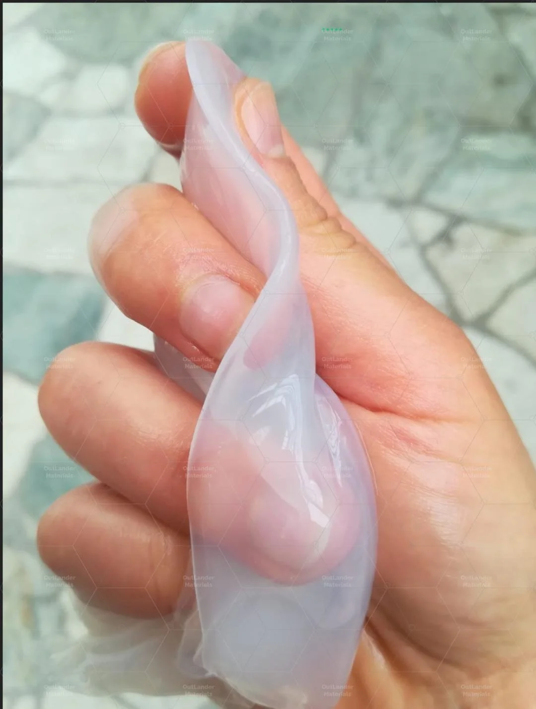Close-up of a person's hand holding a transparent, flexible, and glossy nanocellulose