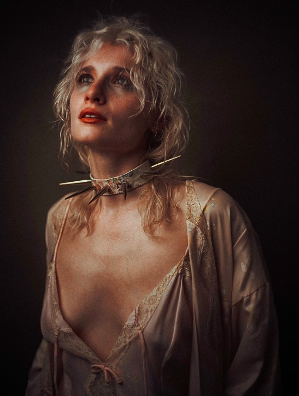 Lorian Gish by SmoothMalik. Blonde figure wearing a choker encircled with long spikes, adorned in pink silk and vintage lace, looking up towards the website text