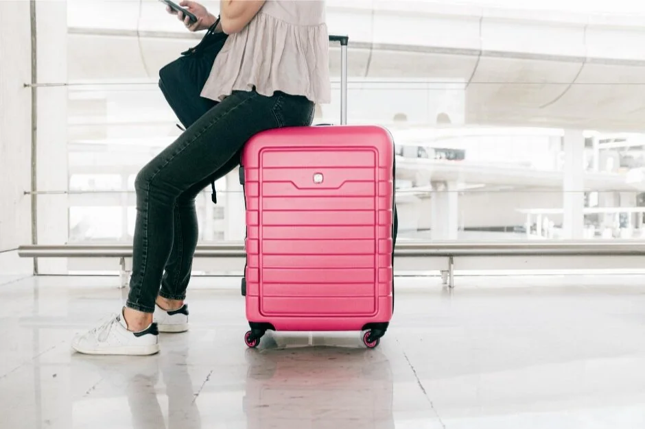 A woman sitting on her suitcase. A doula can help you prepare to travel with baby.