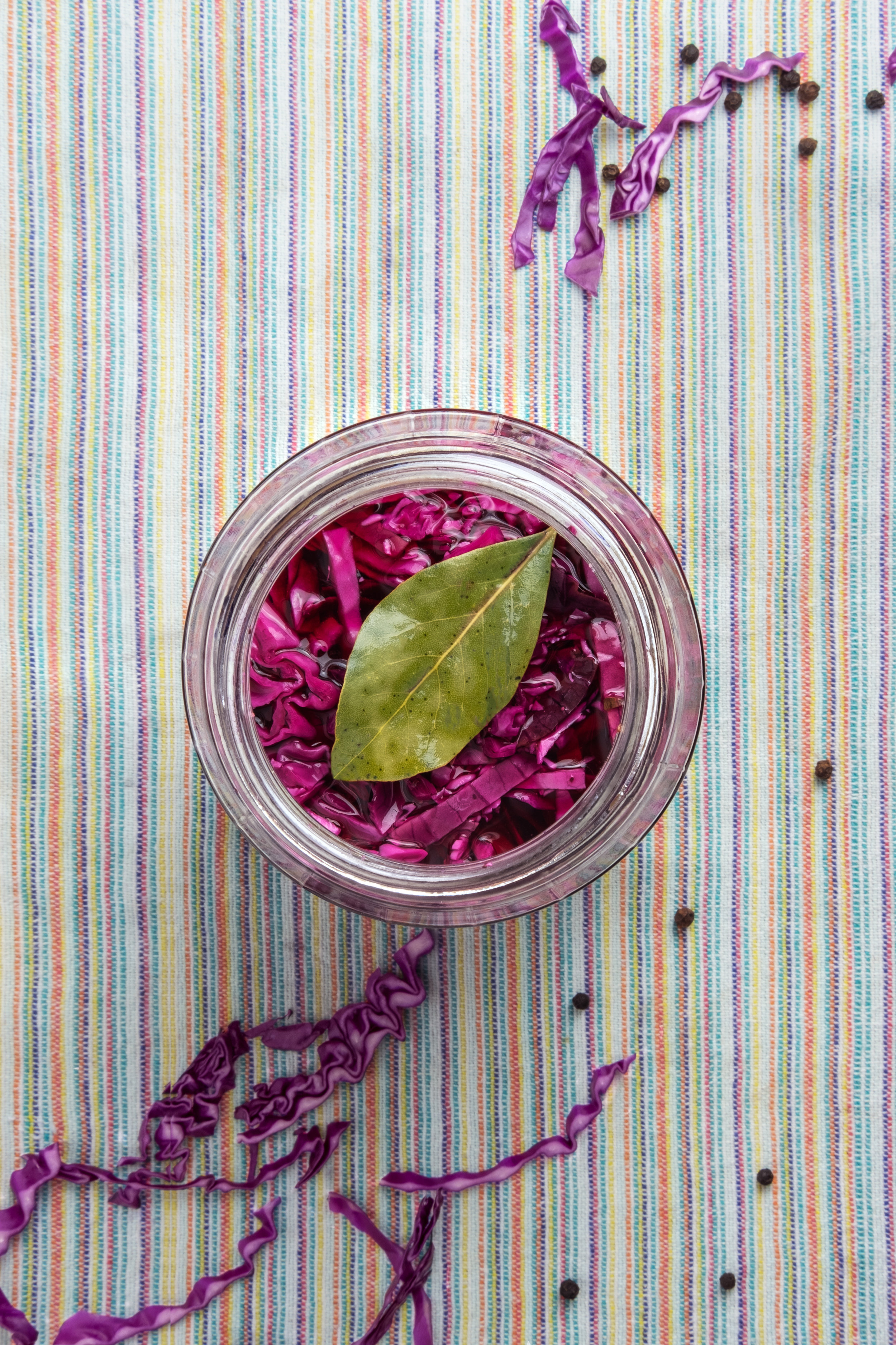  Glass jar of red pickled cabbage on a striped napkin. 