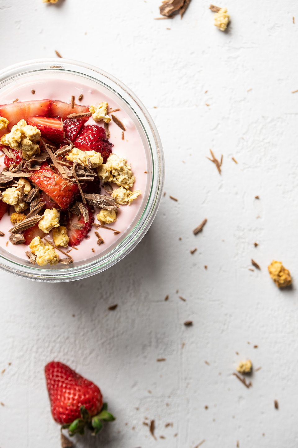  Creamy strawberry and greek yogurt with granola, strawberries and shaved chocolate on textured white background. 