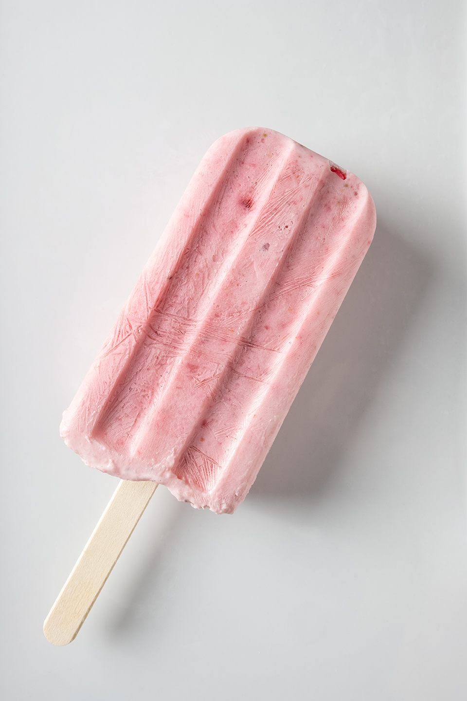  Creamy strawberry and greek yogurt popsicle on a white background. Shot from above. 
