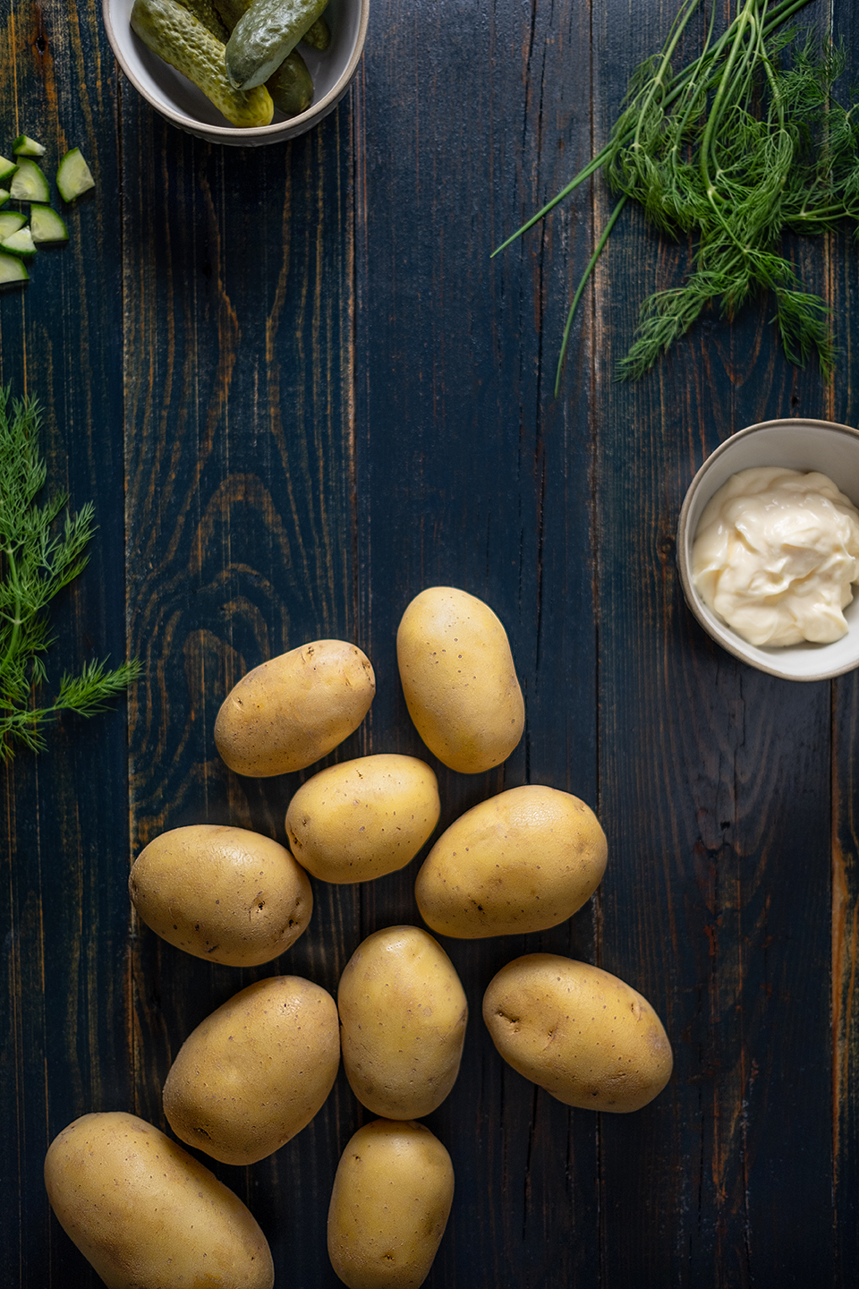  Potatoes, mayonnaise, dill and small pickles on a rustic blue background.  