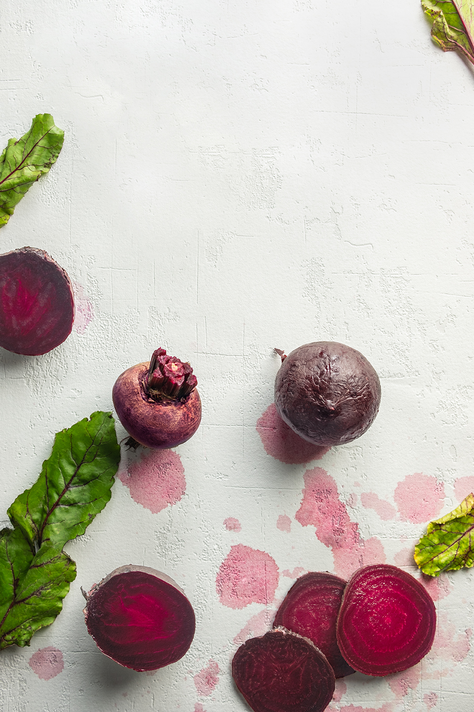  Sliced raw and roasted beets on a white background stained by beet juice.  