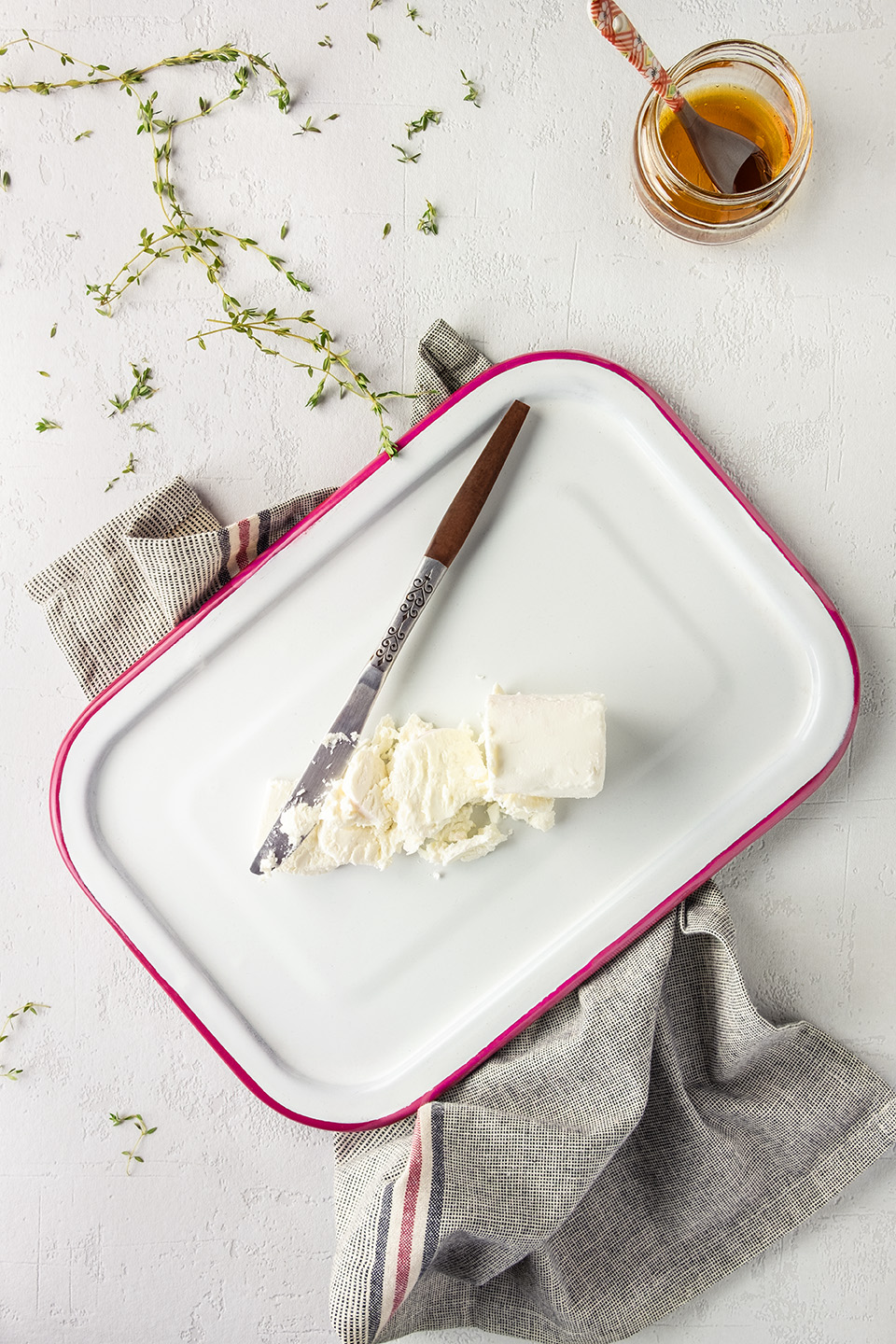  Chevre goat cheese on white enamel cutting board with thyme and honey. 