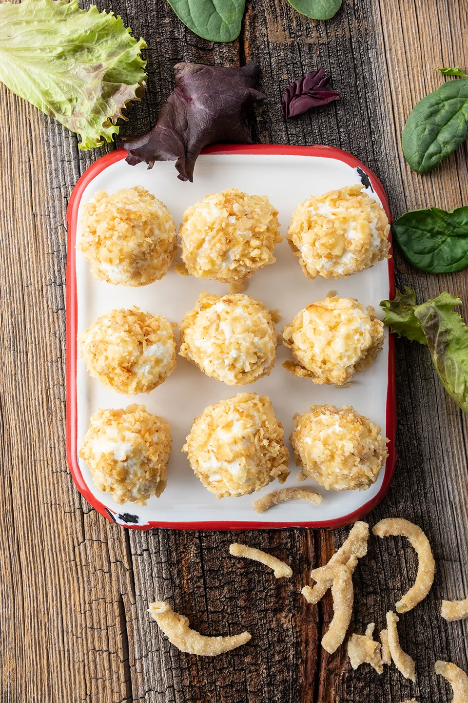  Nine honey goat cheese balls coated in crushed crispy onions on a white enamel platter.  Rustic barnwood background.  